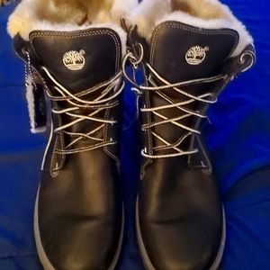 Women’s black combat style Timberland boots trimmed in off white/gray fur.